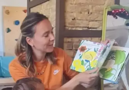 Irene lee un cuento ilustrado a los peques, sentados de espaldas