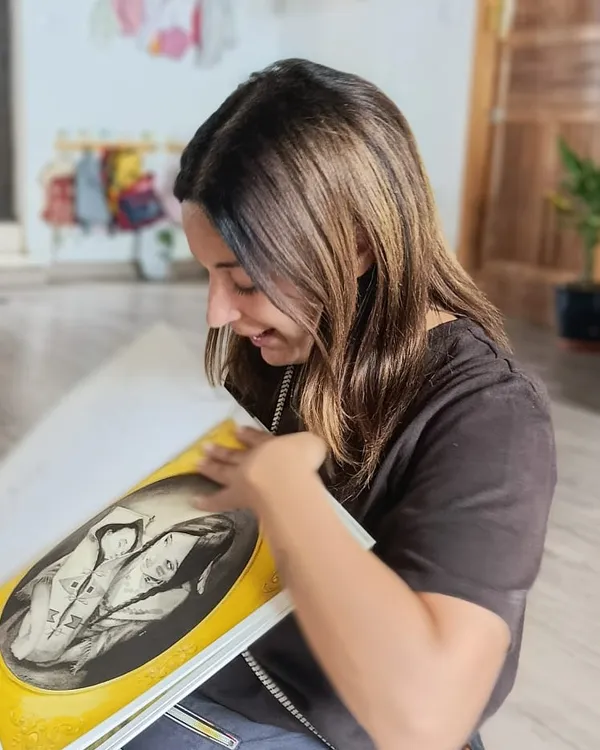 Marta, sentada en el suelo de la sala, lee un cuento ilustrado y sonríe