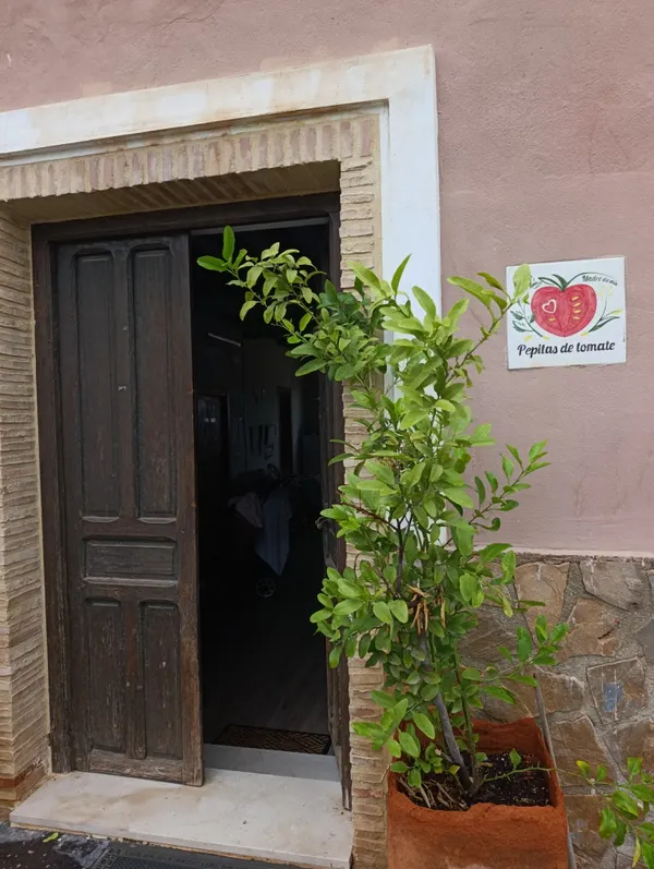 La puerta de madera de Pepitas de tomate, con su cartel de azulejo y un limonero en una maceta de barro